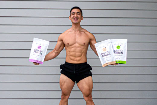 Fit, smiling man holding three Boba Tea Protein bags, showcasing taro, classic, and matcha flavors.