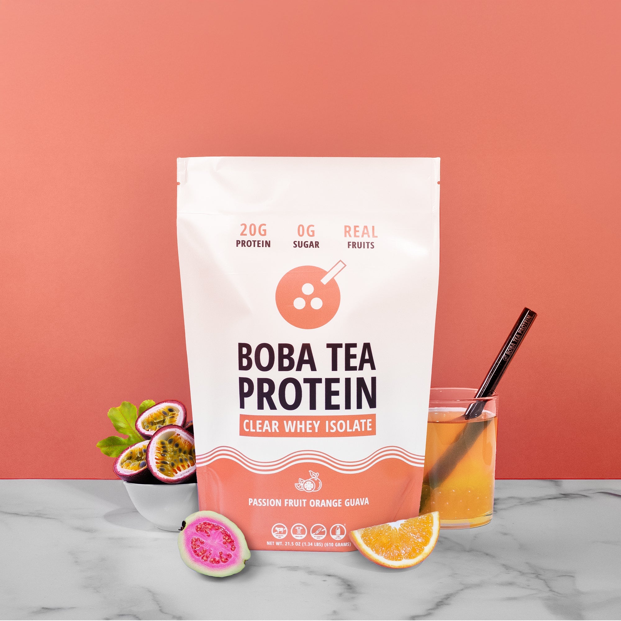 Boba Tea Protein package with a glass of juice and fruit on a marble surface against a pink background