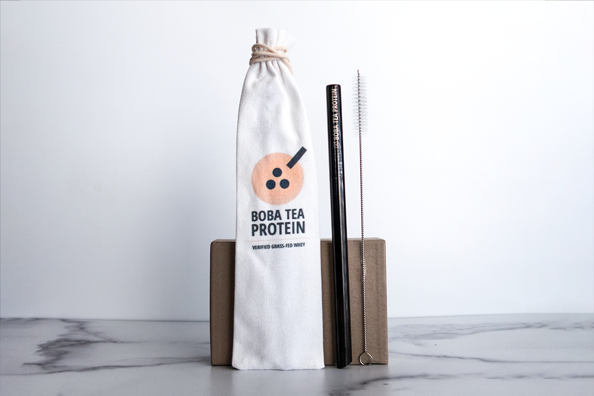 Boba Tea Protein pouch with metal straw, cleaning brush, and a small brown box displayed on a surface.