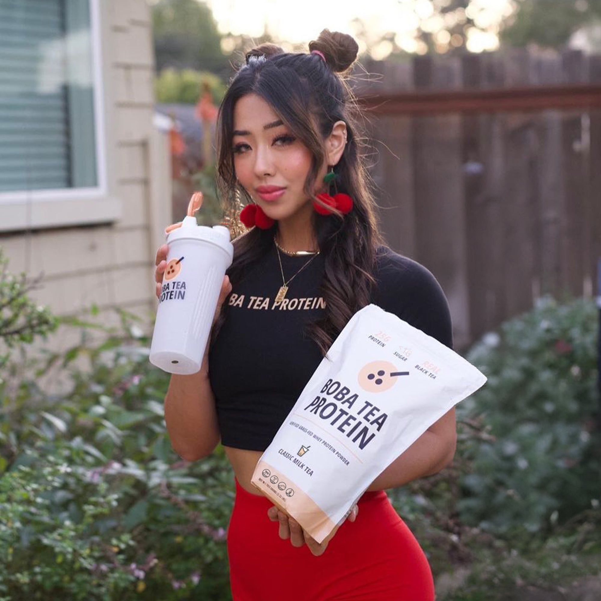 Woman holding Boba Tea Protein shaker and package outdoors
