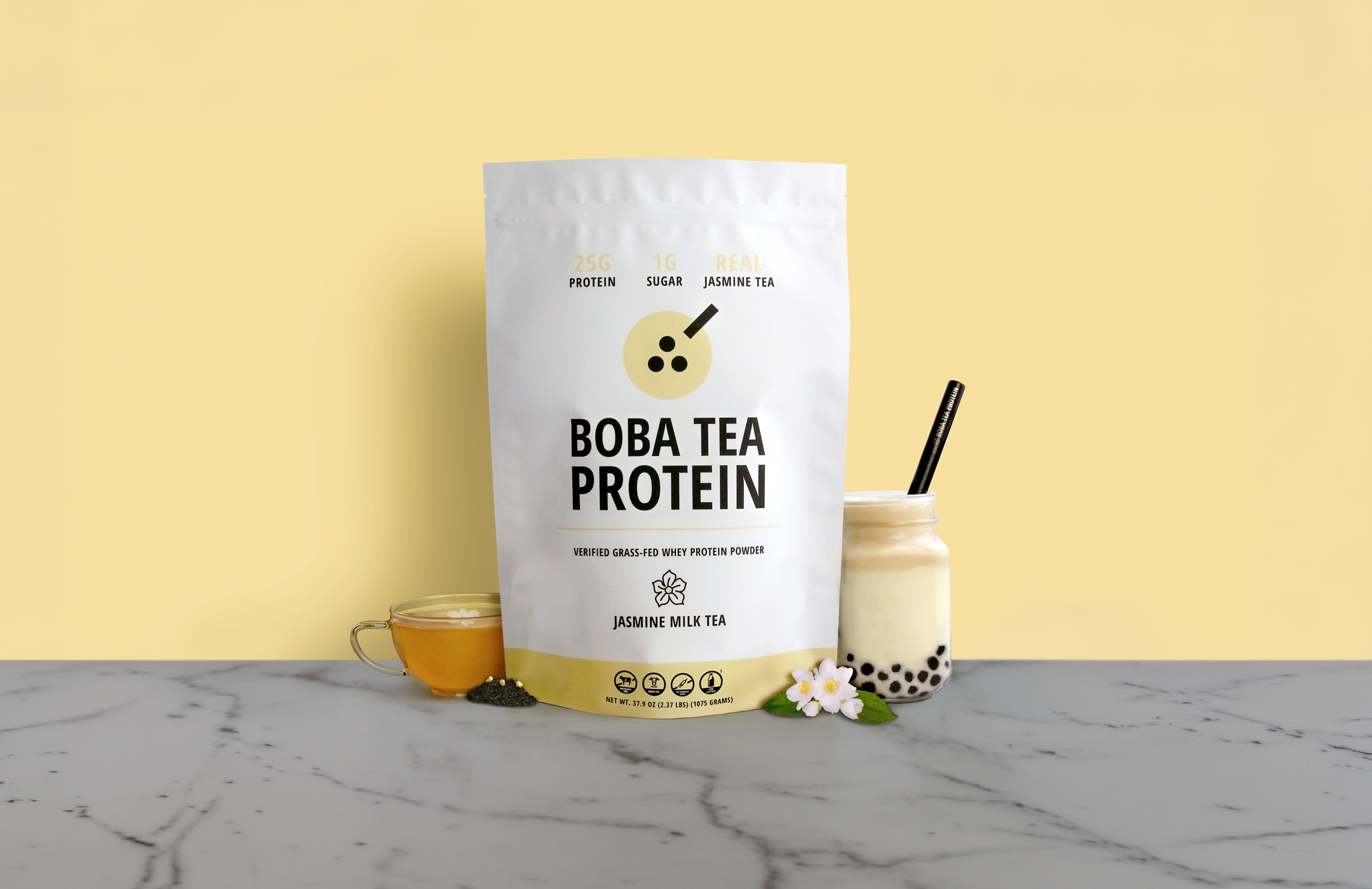 Bag of Boba Tea Protein Jasmine Milk Tea with a cup of tea and boba pearls on a yellow background