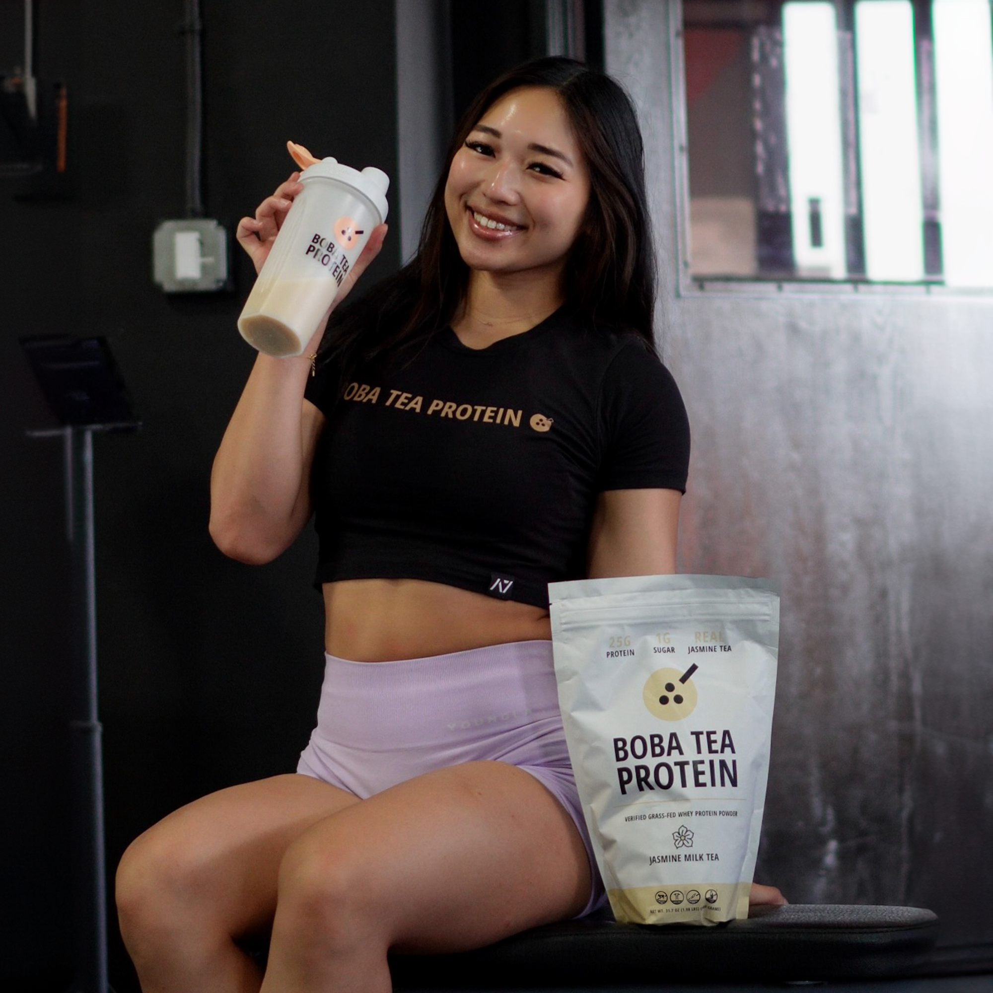 Woman holding a protein shake and package with 'Boba Tea Protein' branding.