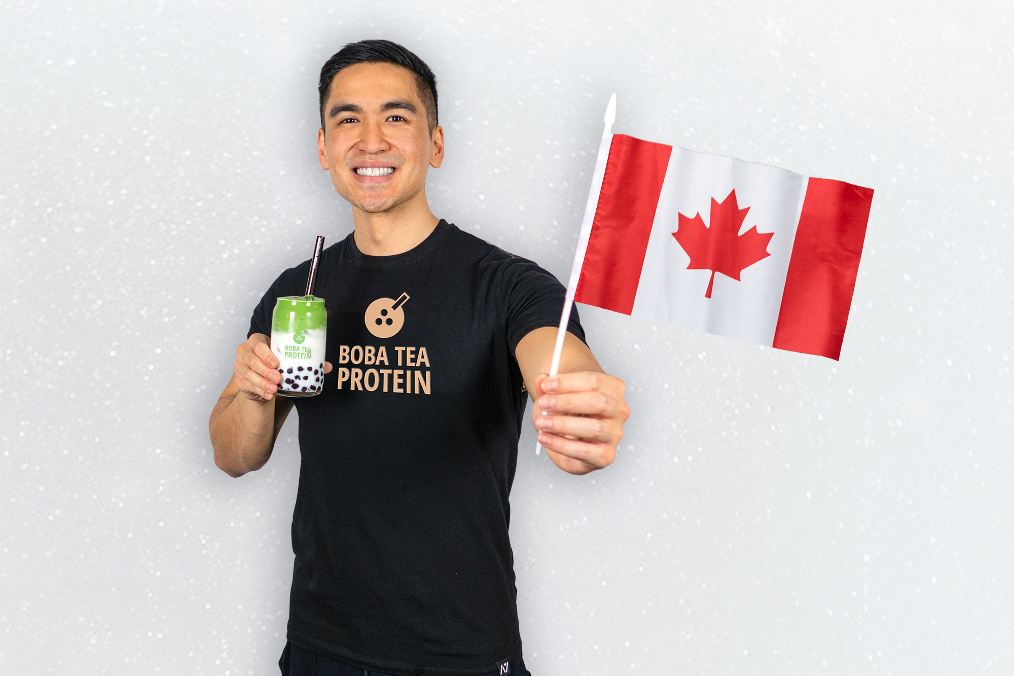 Smiling man in Boba Tea Protein shirt holding honeydew boba drink and Canadian flag.