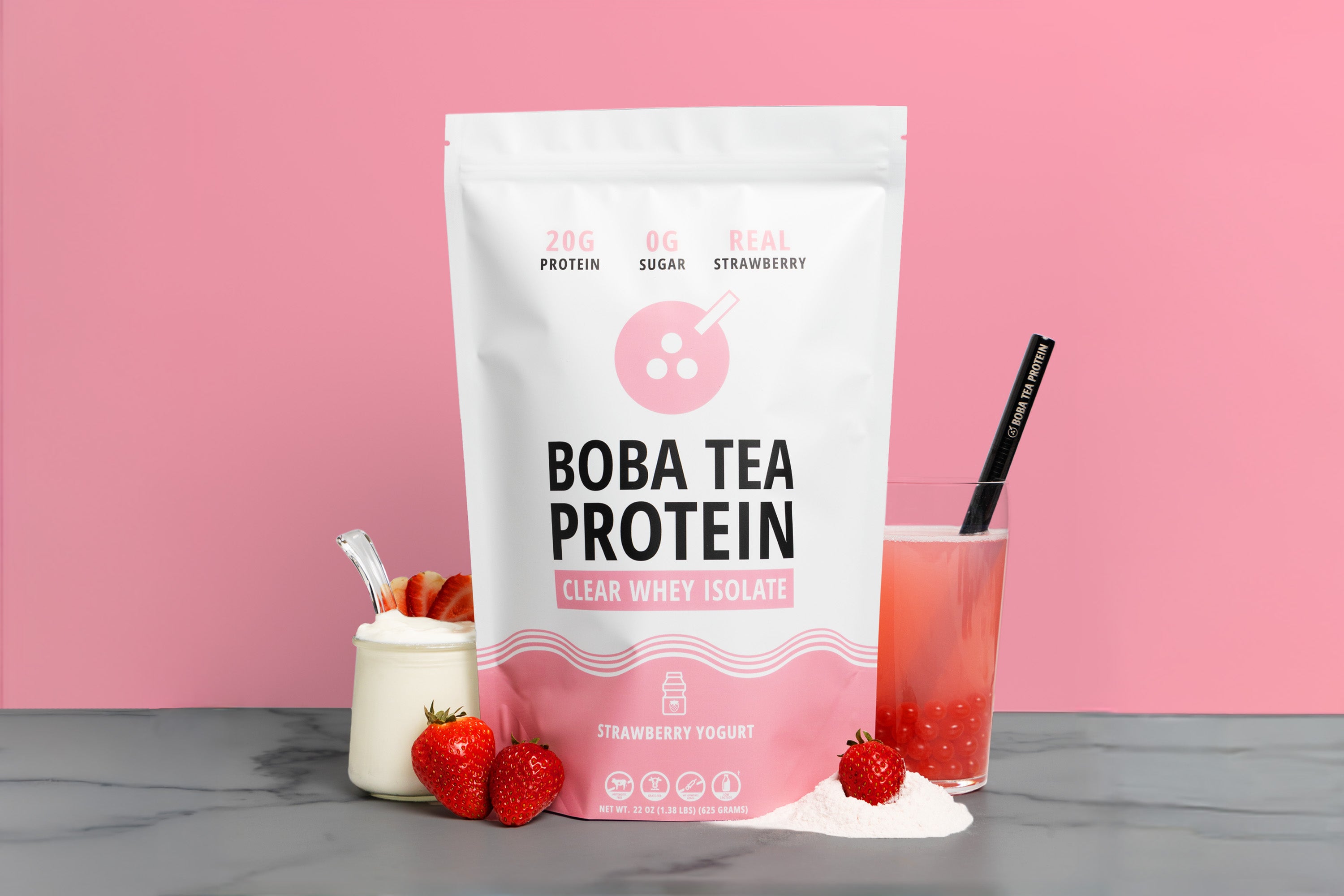 Boba tea protein package with a glass of strawberry yogurt clear whey and strawberries on a pink background