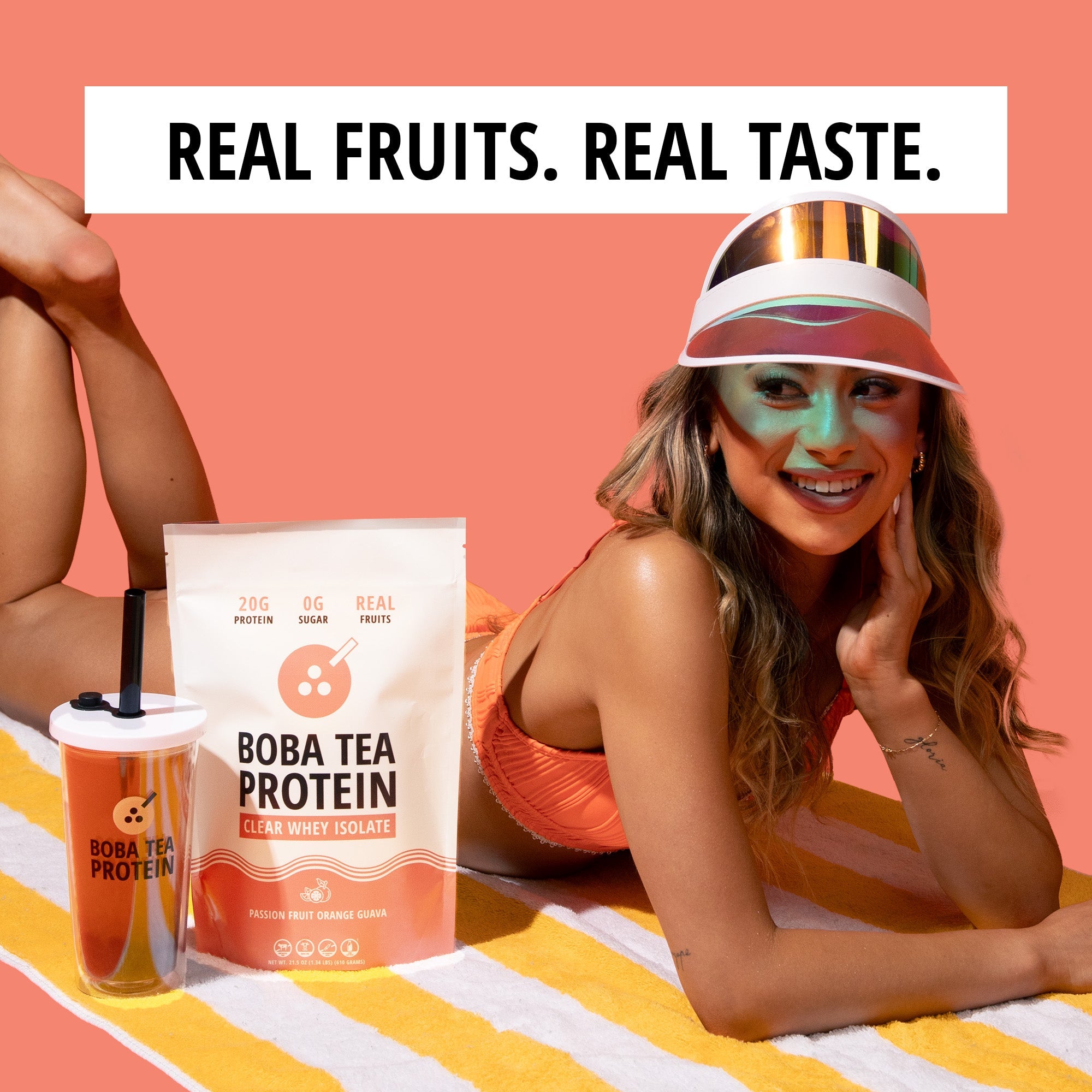 Woman lying on a towel with Boba Tea Protein packaging and a cup, against a peach background.