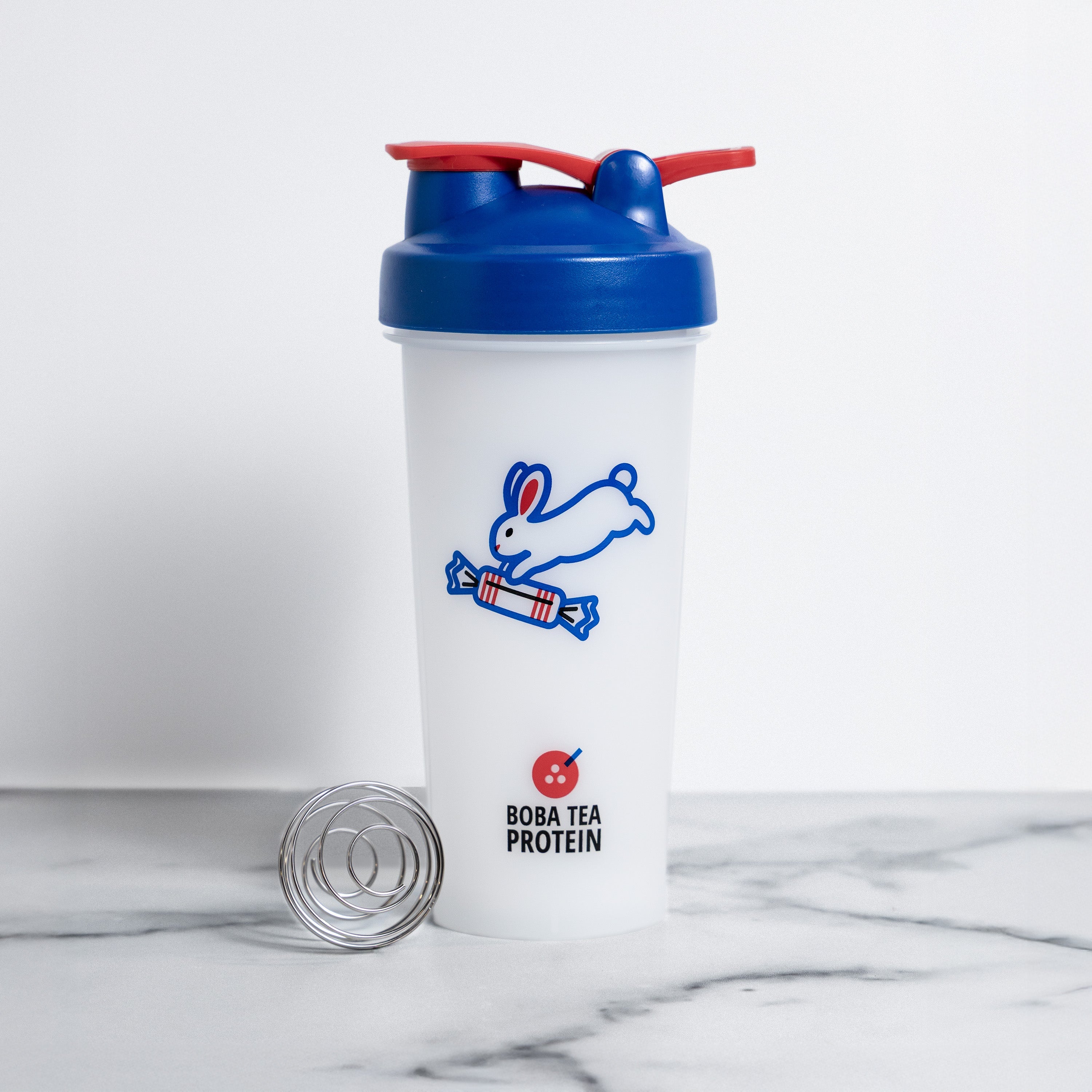 Shaker bottle with blue cap and rabbit logo on a marble surface